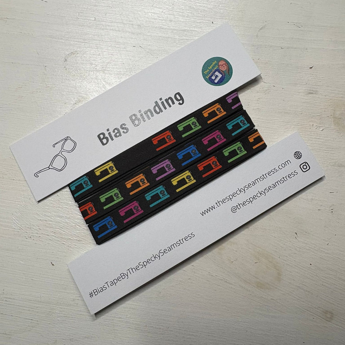 Colorful bias binding strip with packaging on a light wooden surface