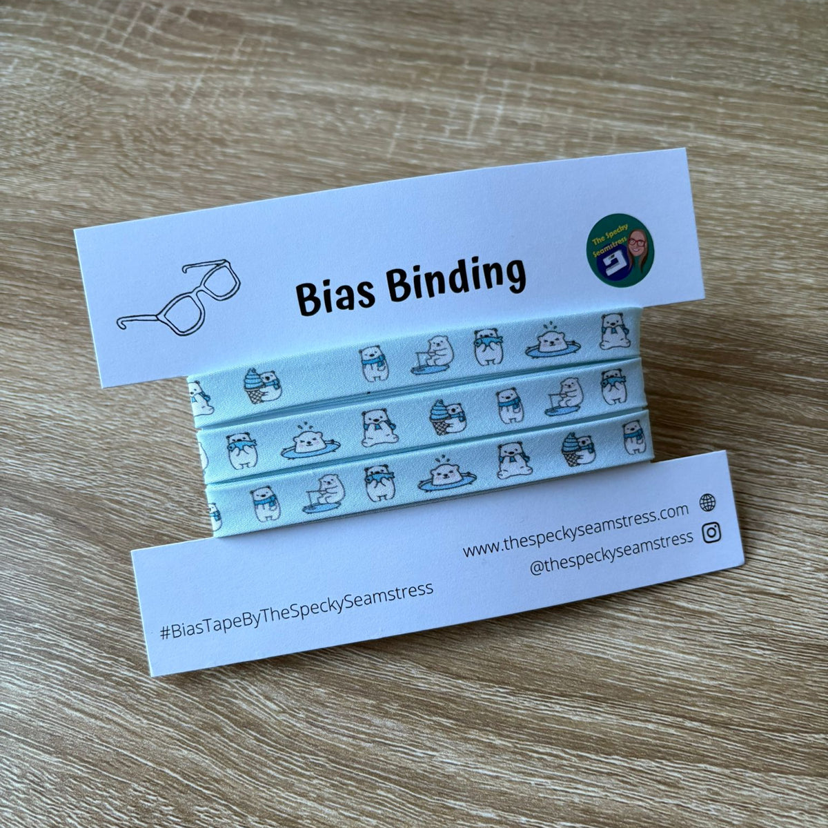Frolicking Polar Bias Binding on a white backing card with branded label on a wooden surface.