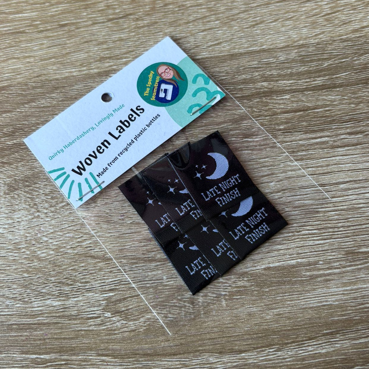 Woven labels in a clear bag with a label card on a wooden surface