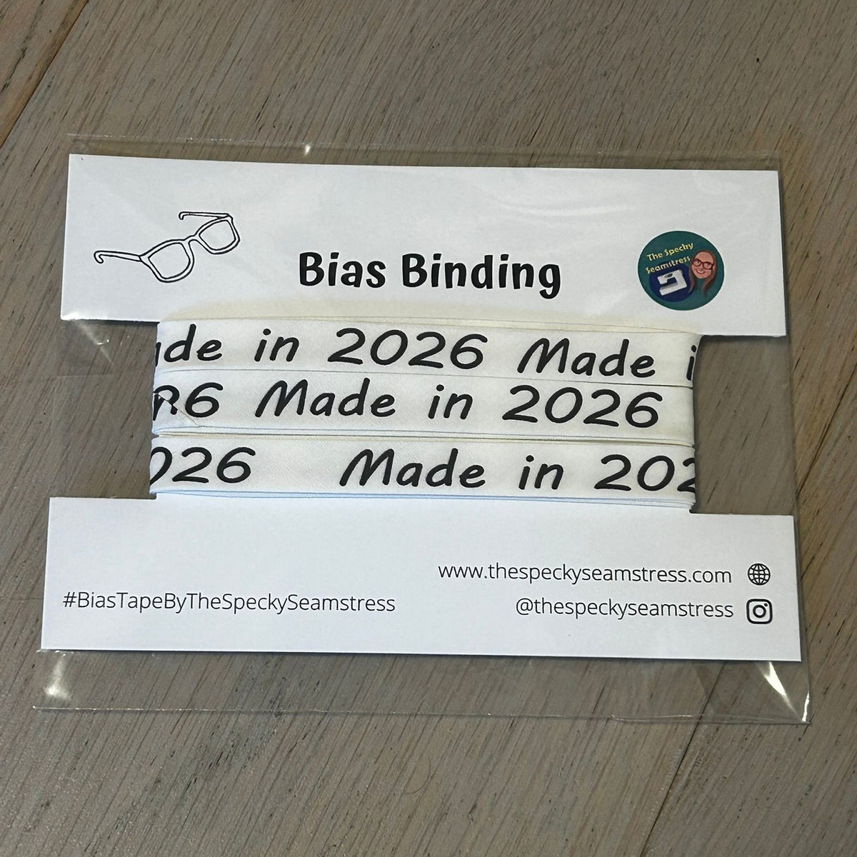 Made in 2026 bias binding tape wrapped around a white card on a wooden surface.
