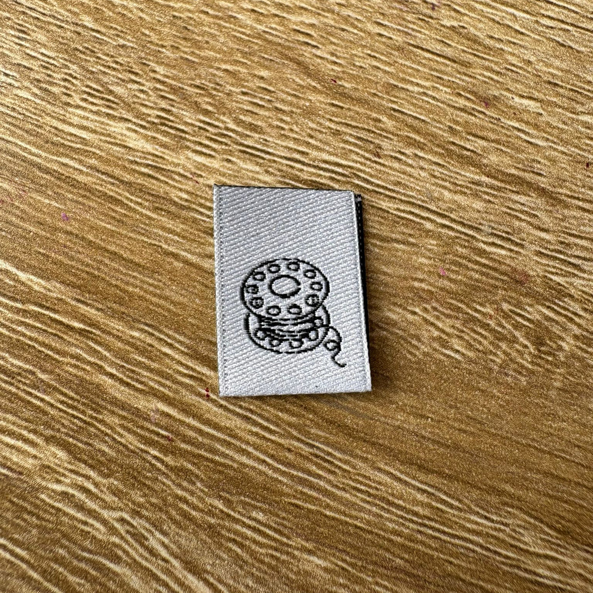 Wovenlabel with spool design on a wooden surface
