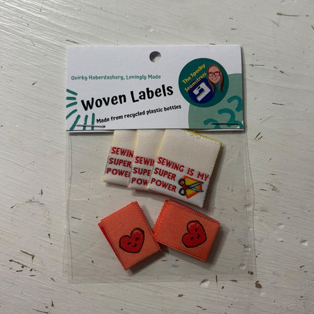 A small clear plastic bag containing two different woven label designs.
