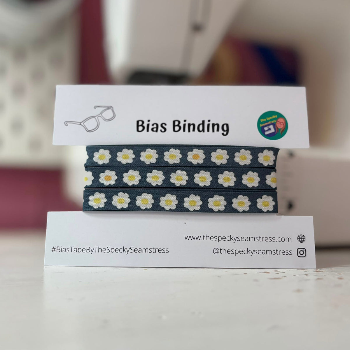 Bias binding with daisy pattern on a stand with branding information.