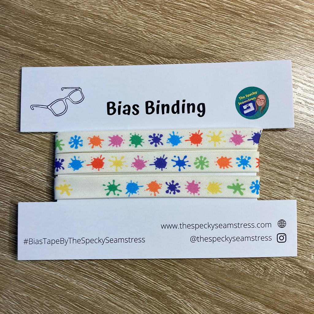 Splat multi-coloured bias binding wrapped on a backing card on a wooden background.